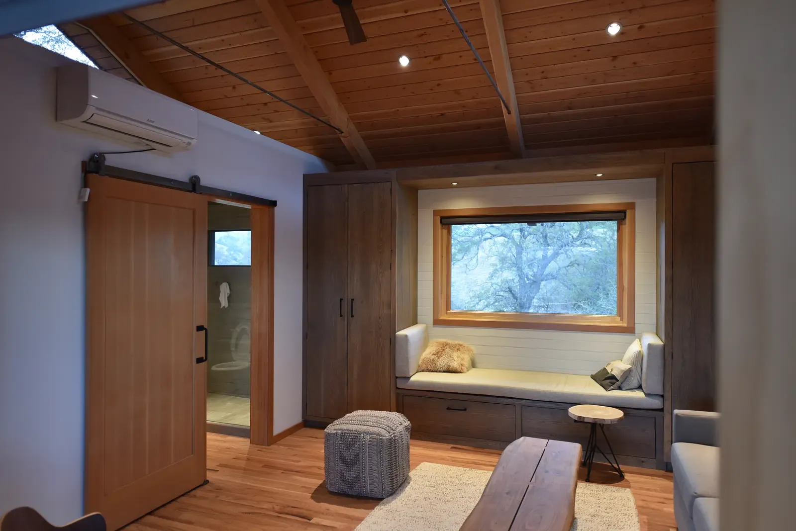Interior under an exposed timber ceiling, window seat and built-in cabinetry