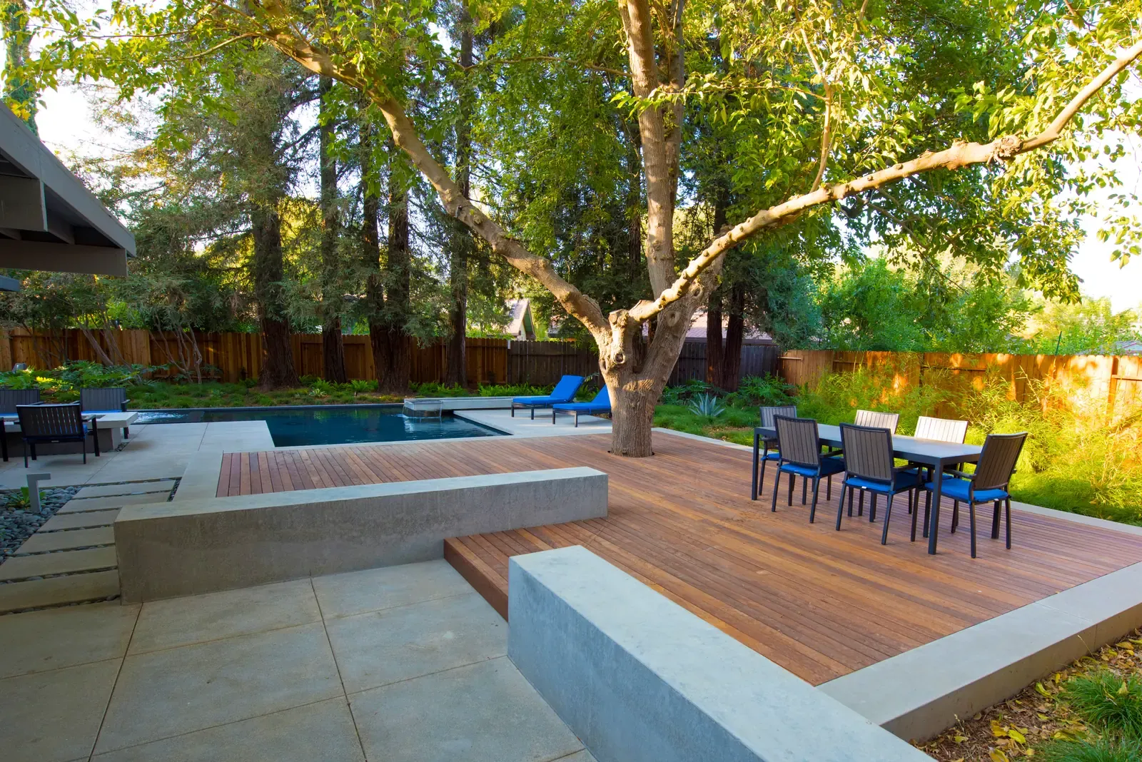 Ipe deck with a dining table under an old oak, spa and pool alongside