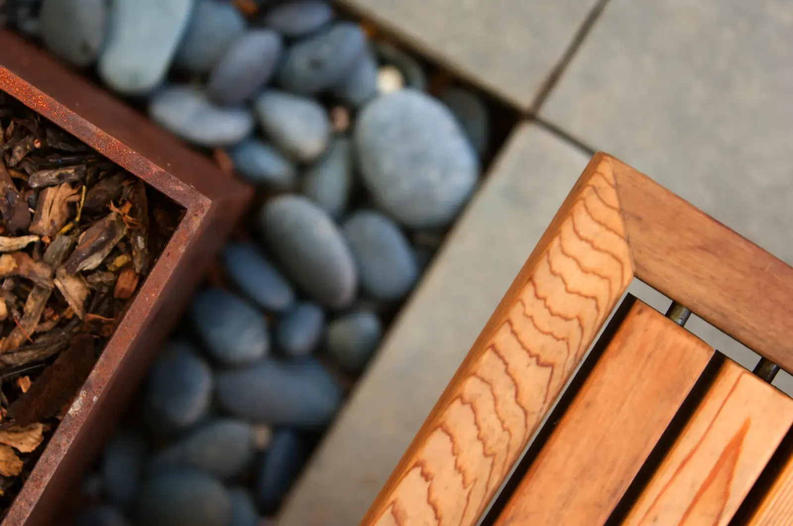 Detail of the weathering-steel planter edge, river cobble and the ipe bench slats