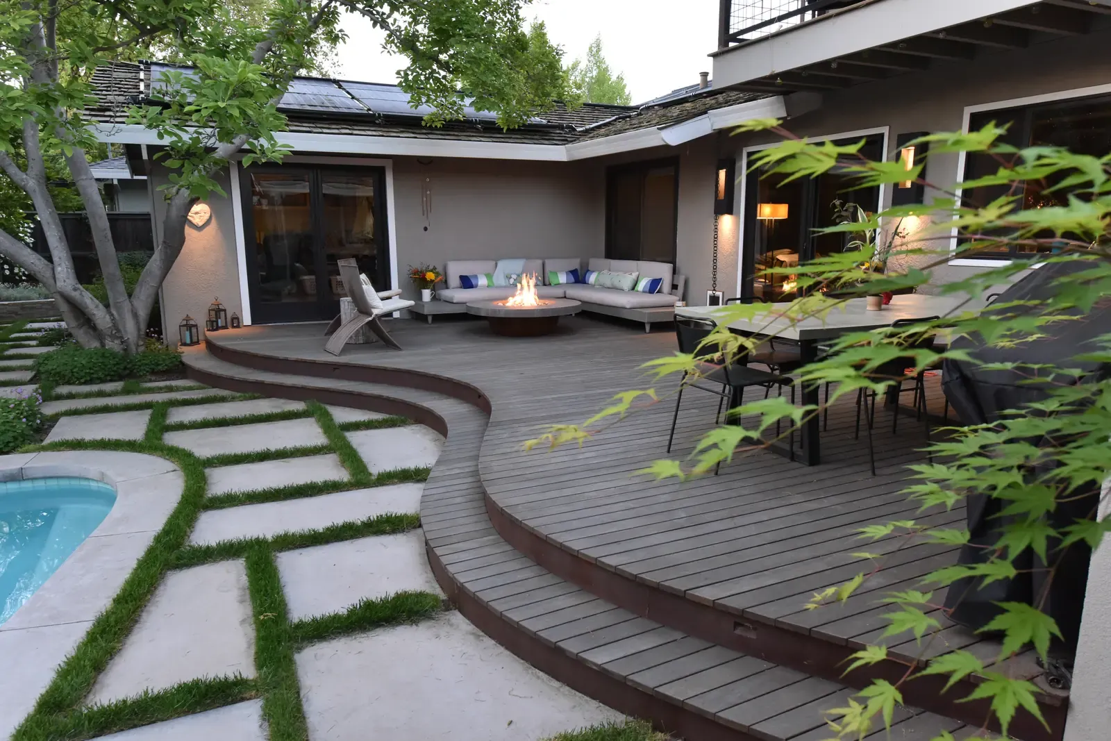 Redwood deck curving past a fire table and Japanese maple to the seating terrace
