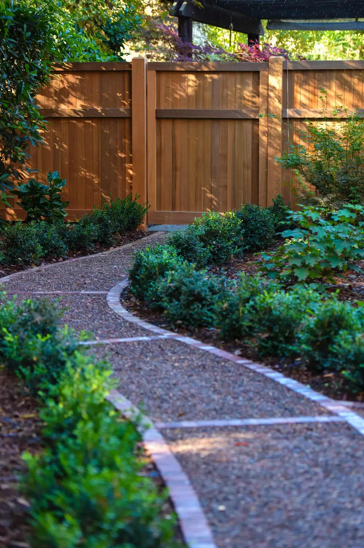 Brick-edged gravel path running past low hedging