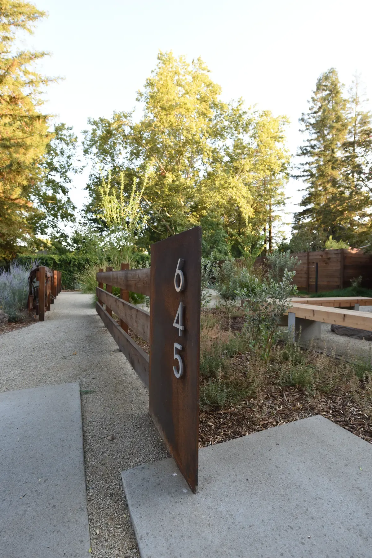 Weathering-steel address panel numbered 645 beside the concrete entry path