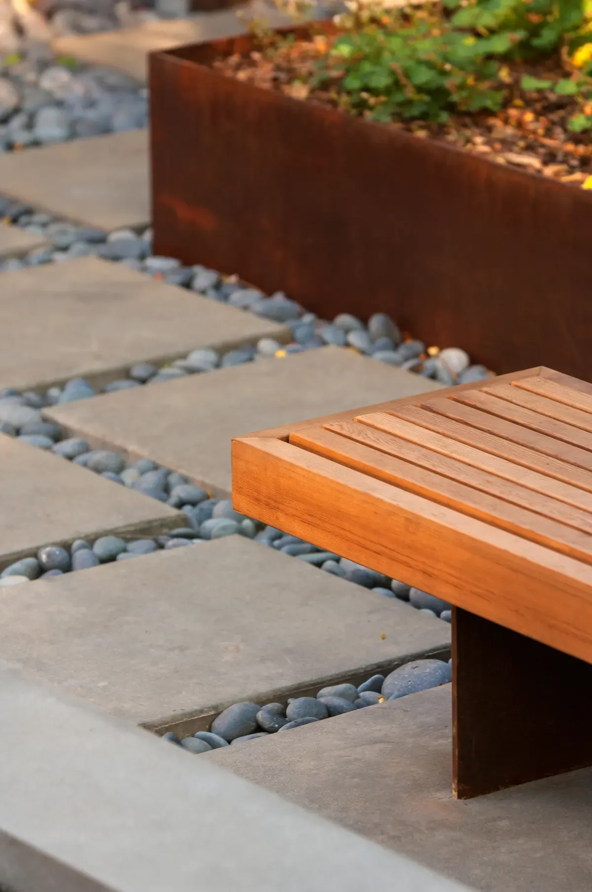 Floating ipe bench beside the paving, cobble strip along the planter