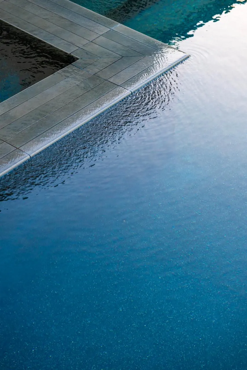 Dark tiled pool edge with rippling water