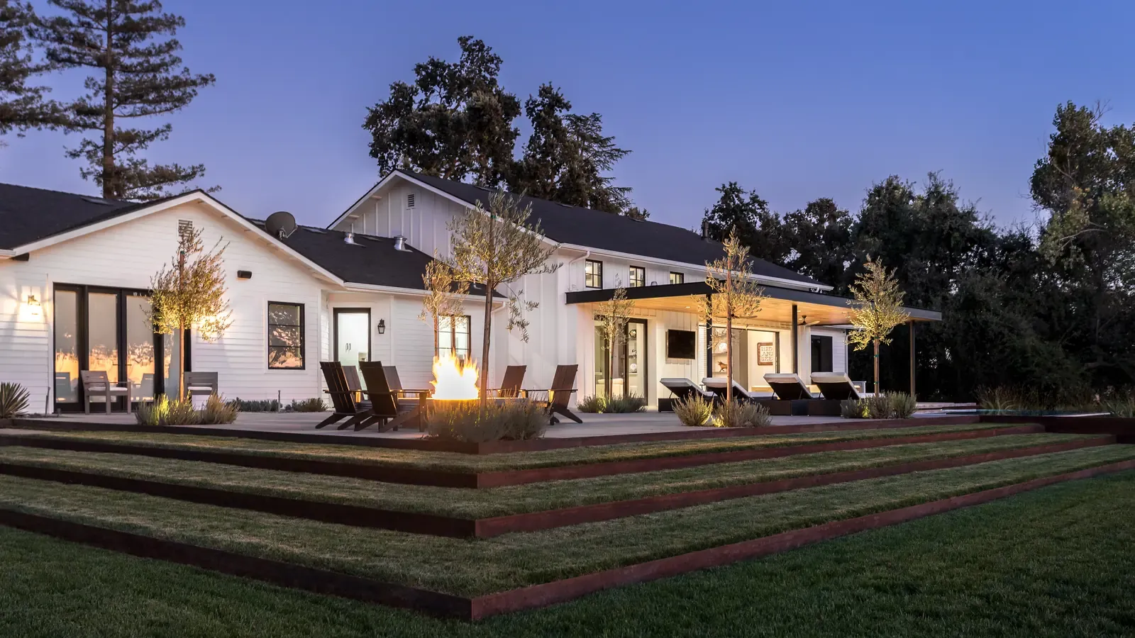 Fire terrace and stepped corten planters on the lawn at dusk