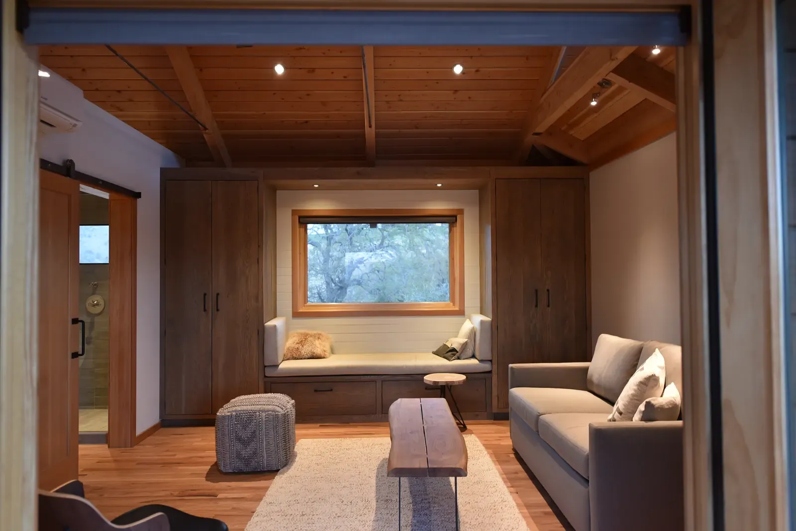 Window seat, sofa and cabinetry beneath the timber ceiling
