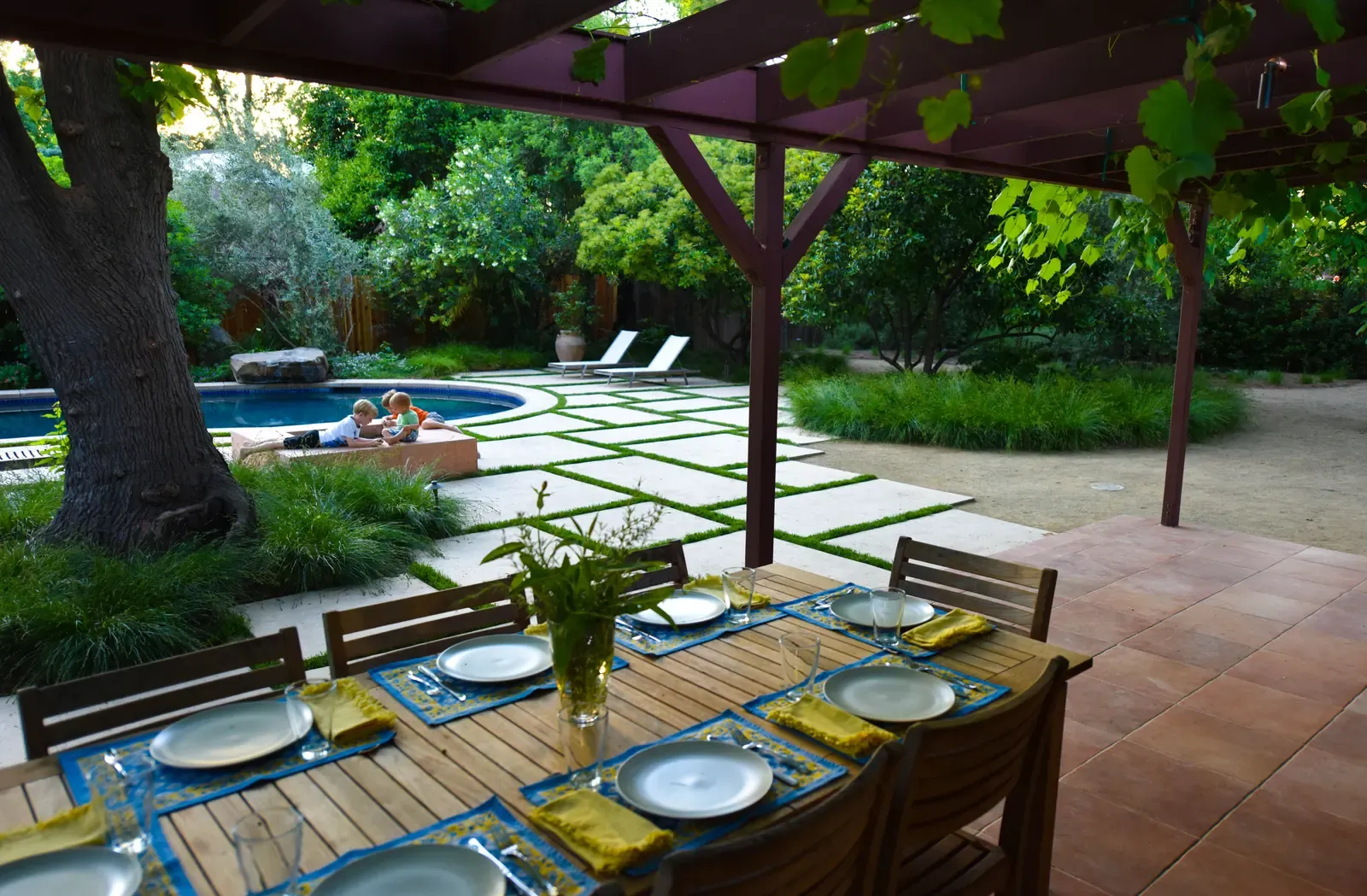 Table set for lunch under the vine-covered arbour, pool beyond