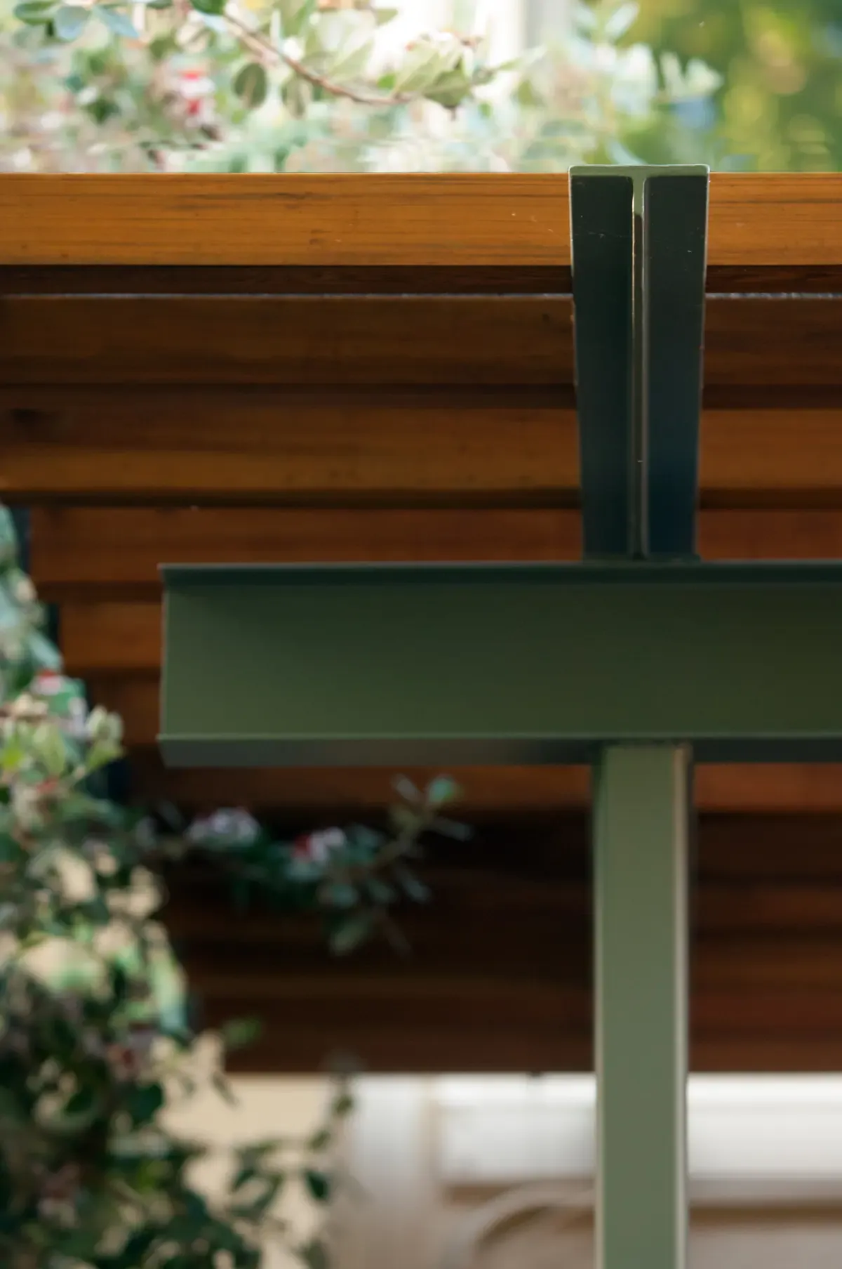 Detail of the green steel post meeting the timber pergola beam