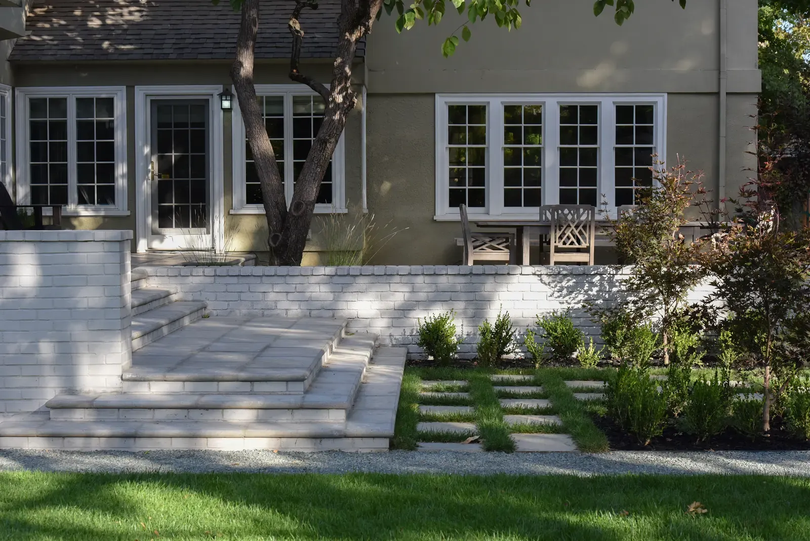 Stone steps and paver path beside the house, clipped planting at the wall
