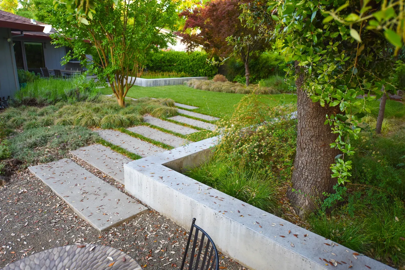 Stepping stones crossing the lawn past a concrete retaining wall