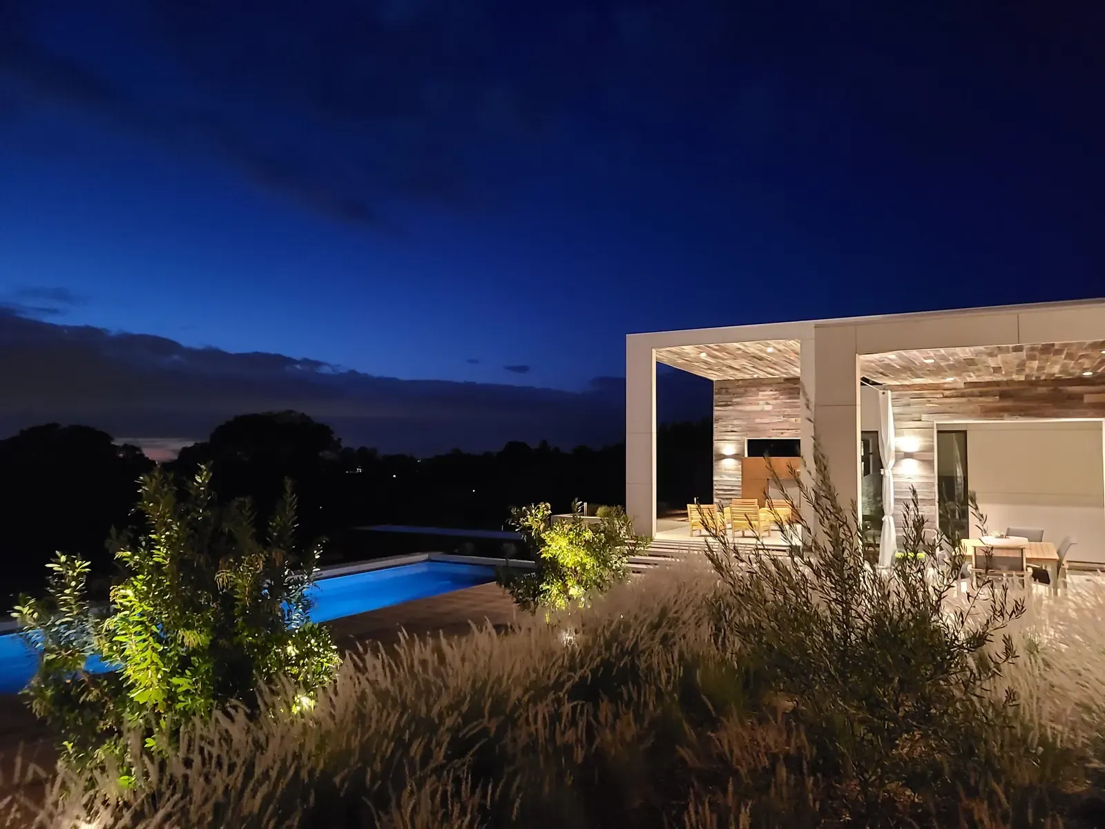 The house and pool at last light, grasses across the foreground