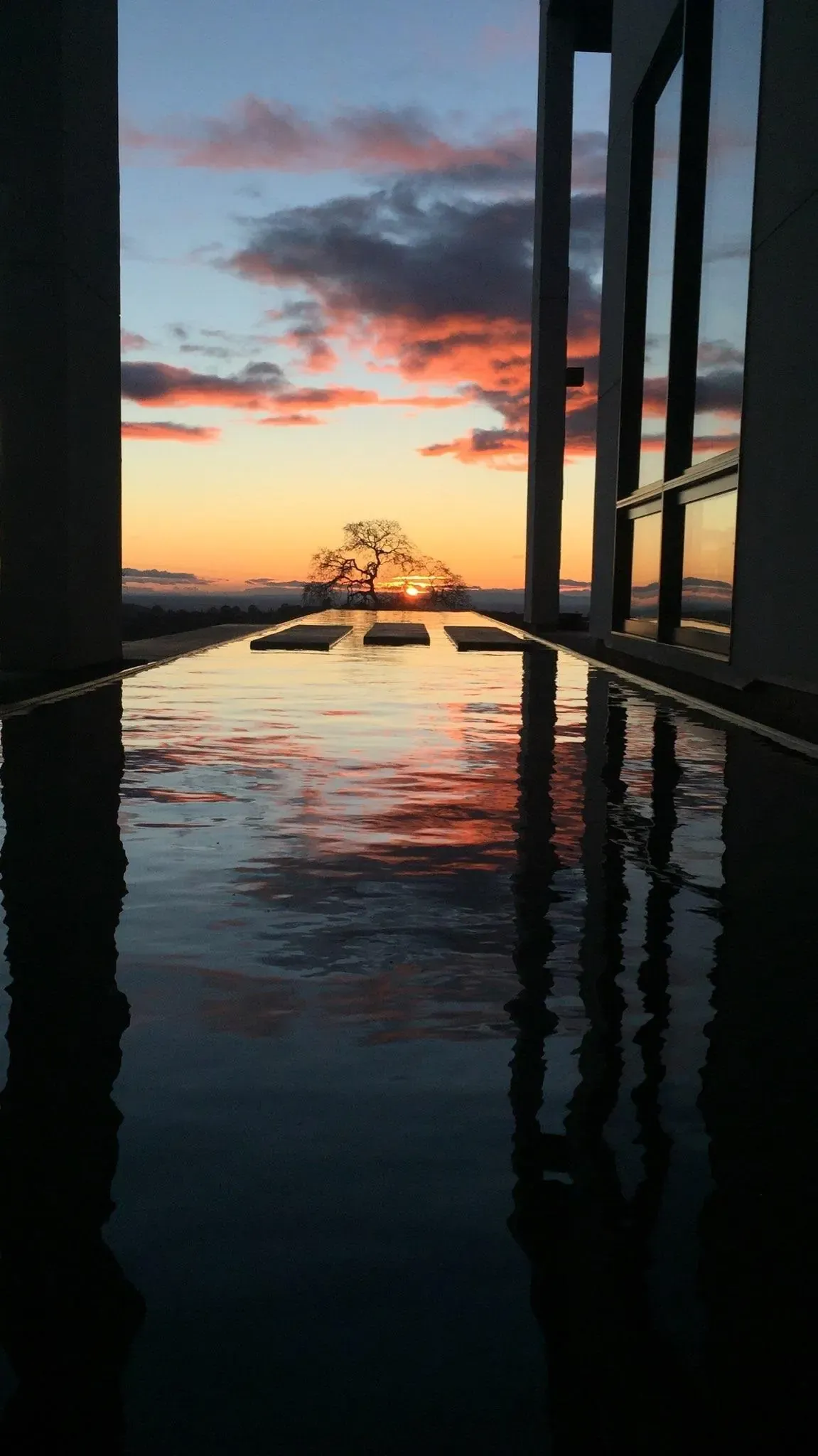 Sunset reflected in the still water between the pavilion columns
