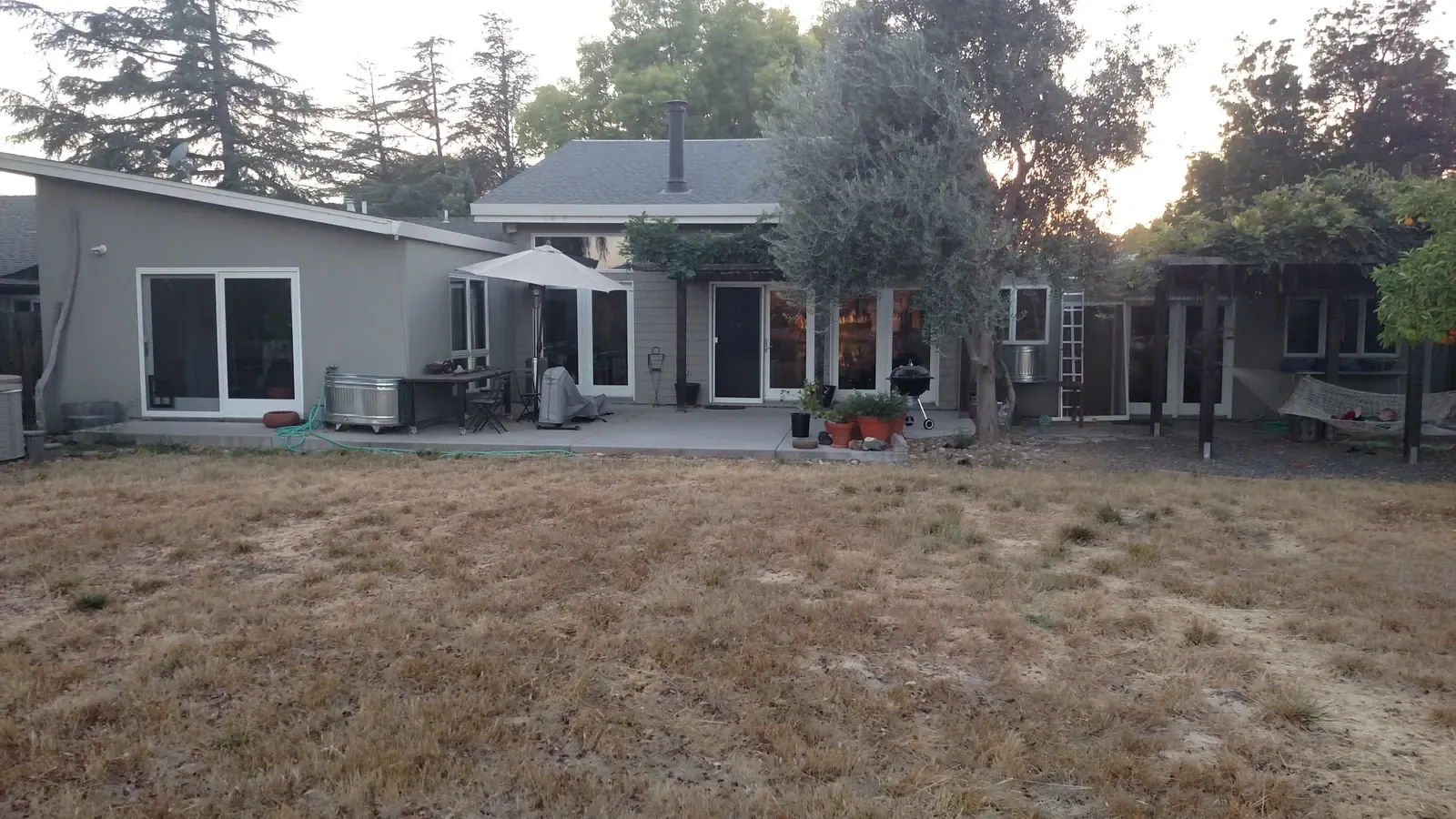 The garden before the work — bare, dry lawn running up to the original house