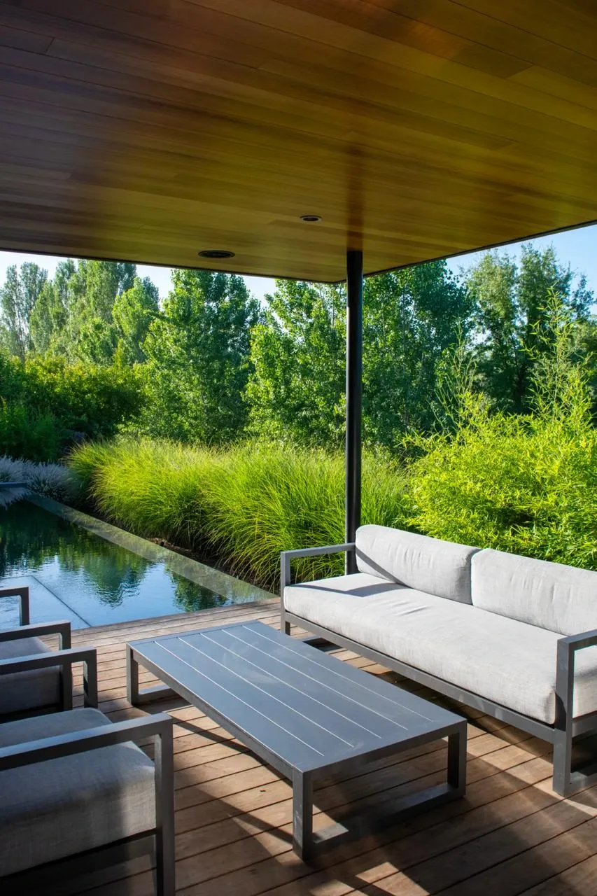 Shaded pavilion seating looking toward the pool and surrounding planting