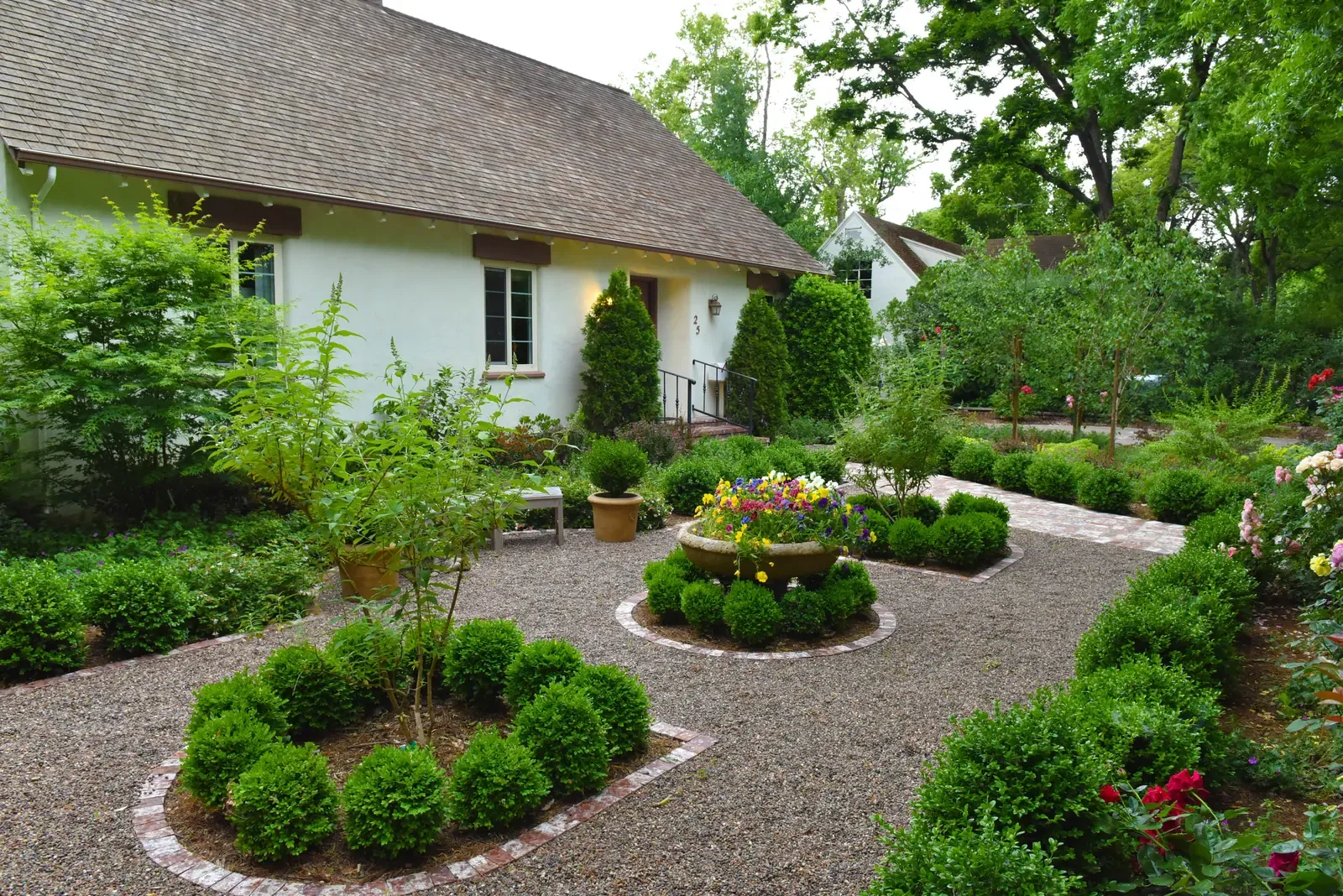 The house across the gravel court, circular planting bed at the centre