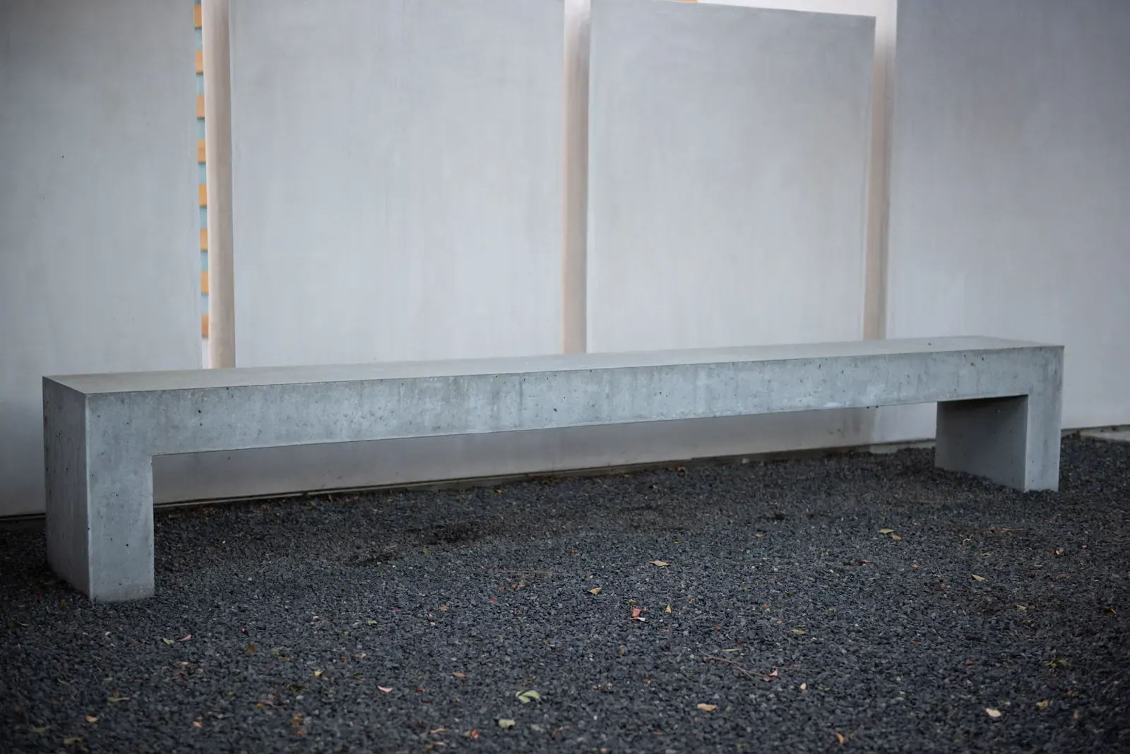 Concrete bench against the white boundary wall on gravel