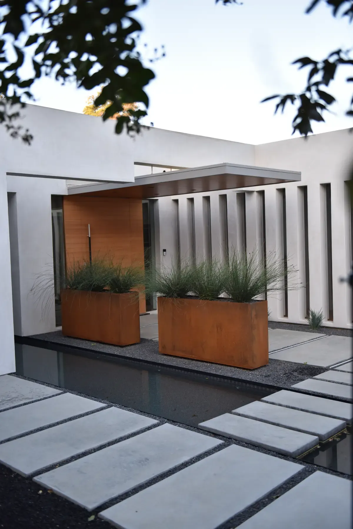 Steel planters and stepping stones between the white walls