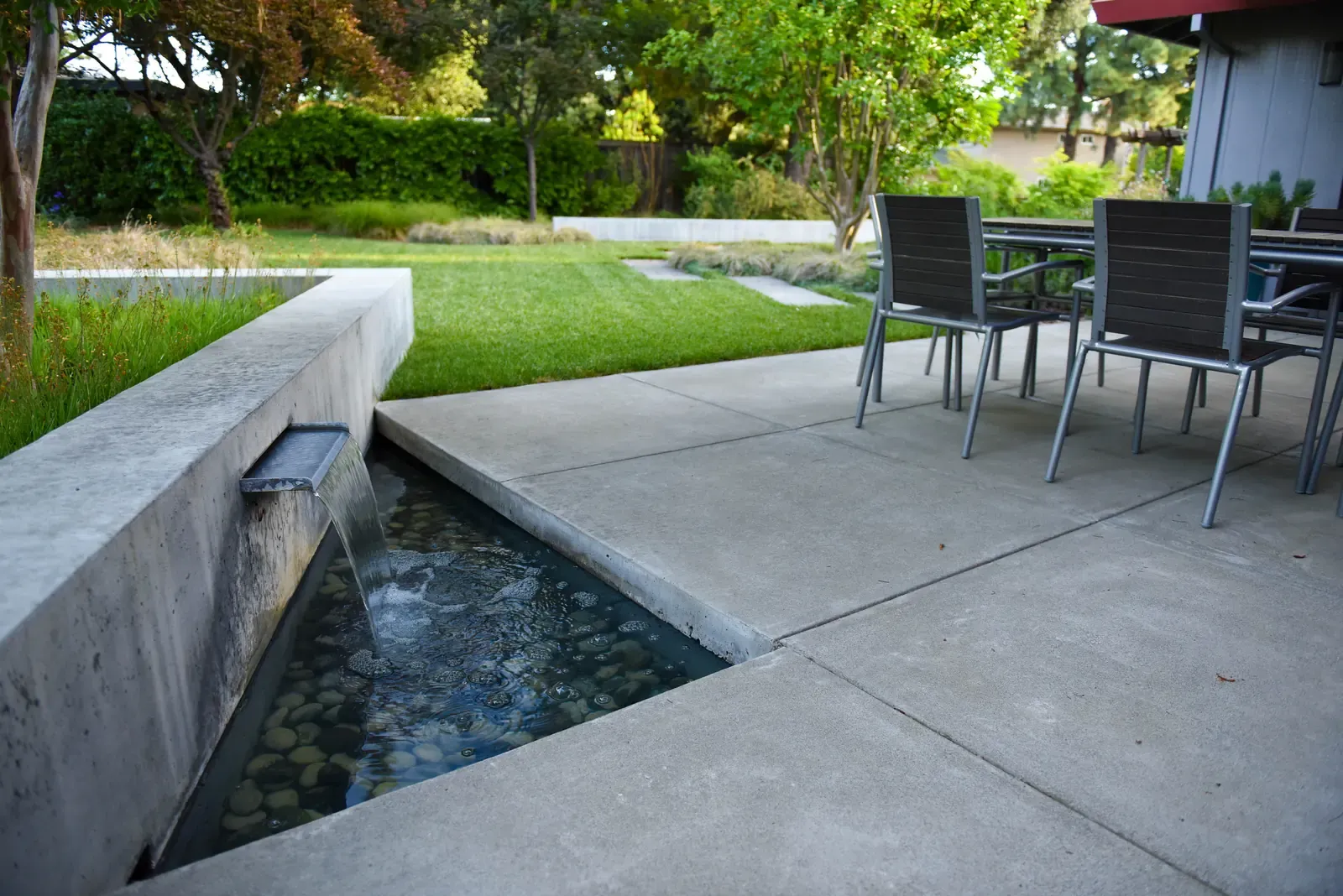 Water channel beside the dining terrace, lawn rising behind