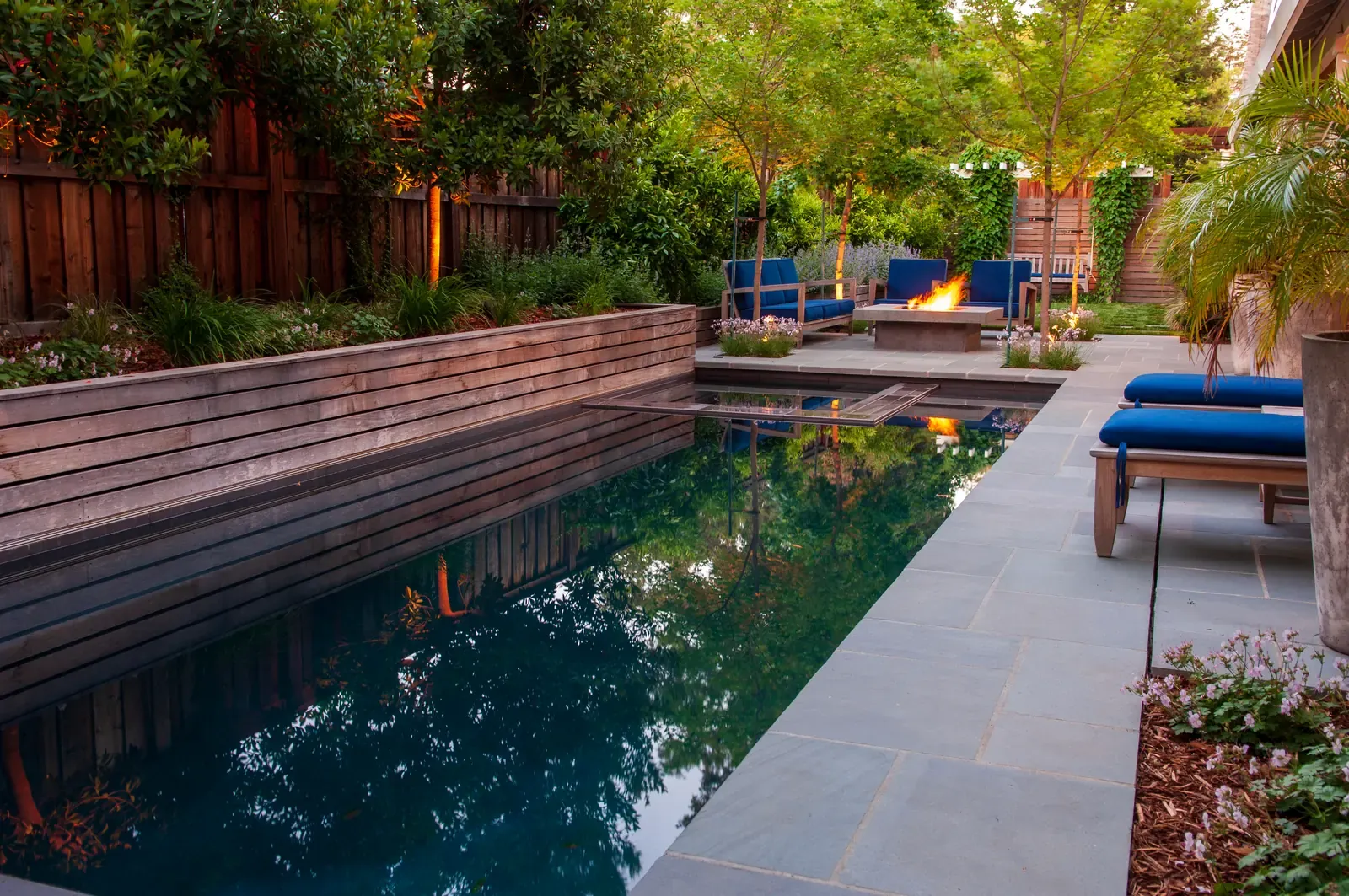 Pool and loungers at dusk, fire alight on the far terrace